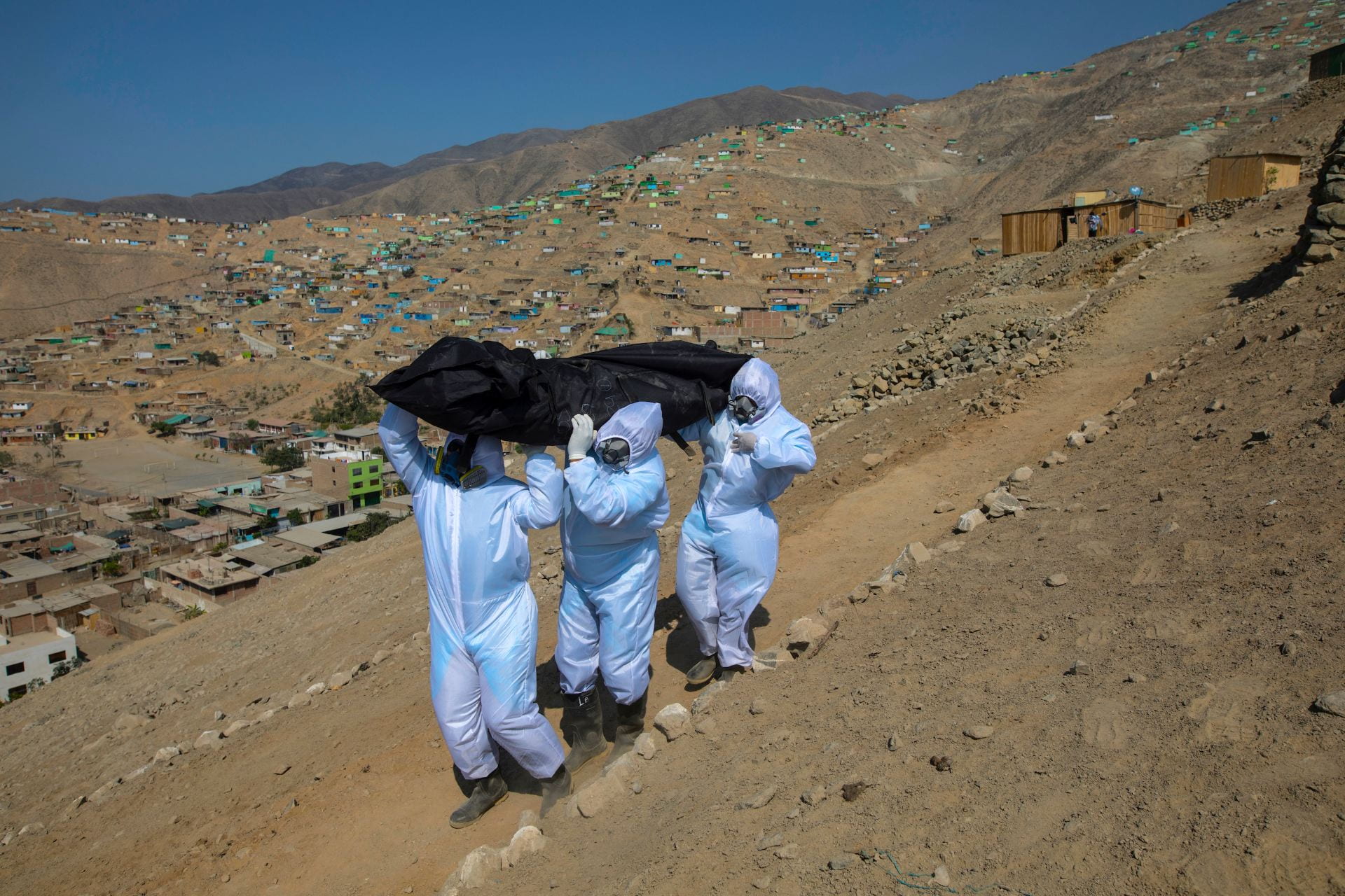 three people carrying a dead body in a desert