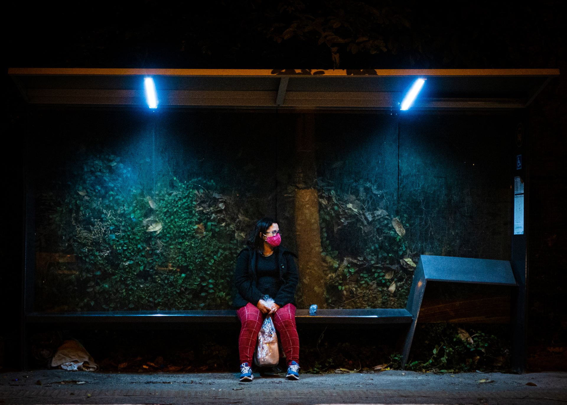 woman in red mask waiting for a bus