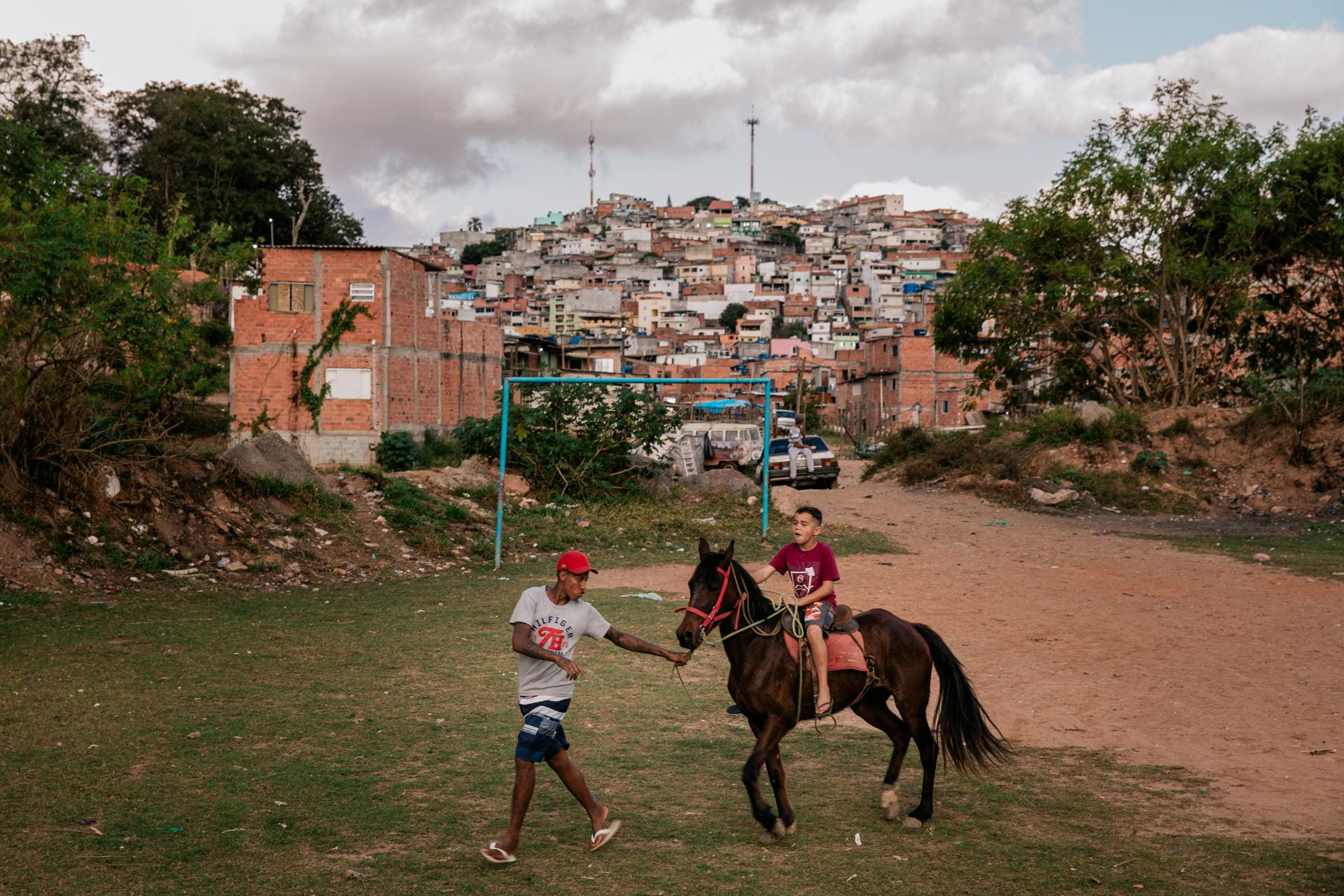 boy on horse in front of favela