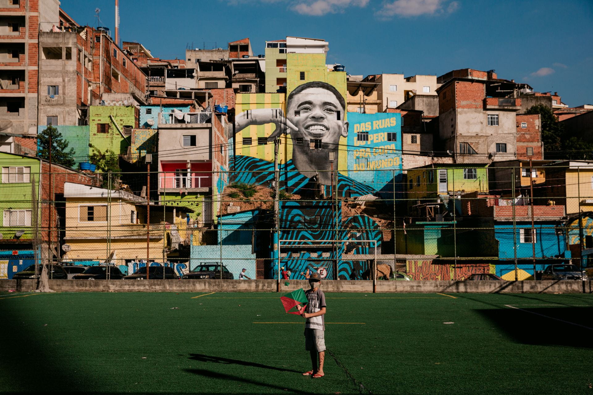 masked boy in sports field in front of murals