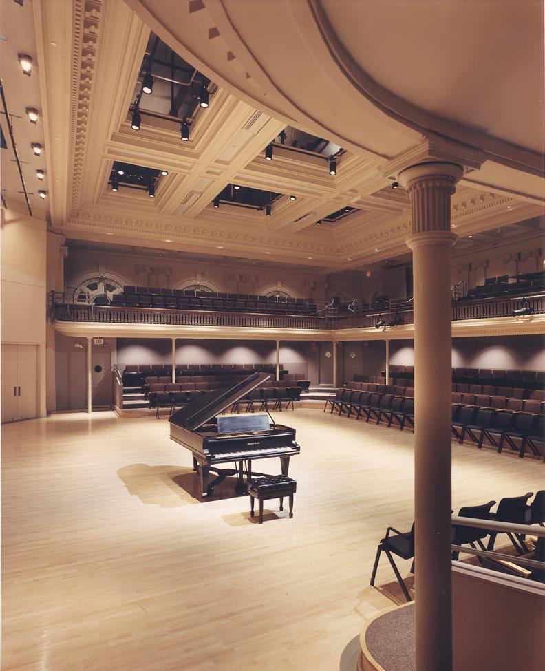 A side view of an empty Lowell Lecture Hall except for a lone piano center stage